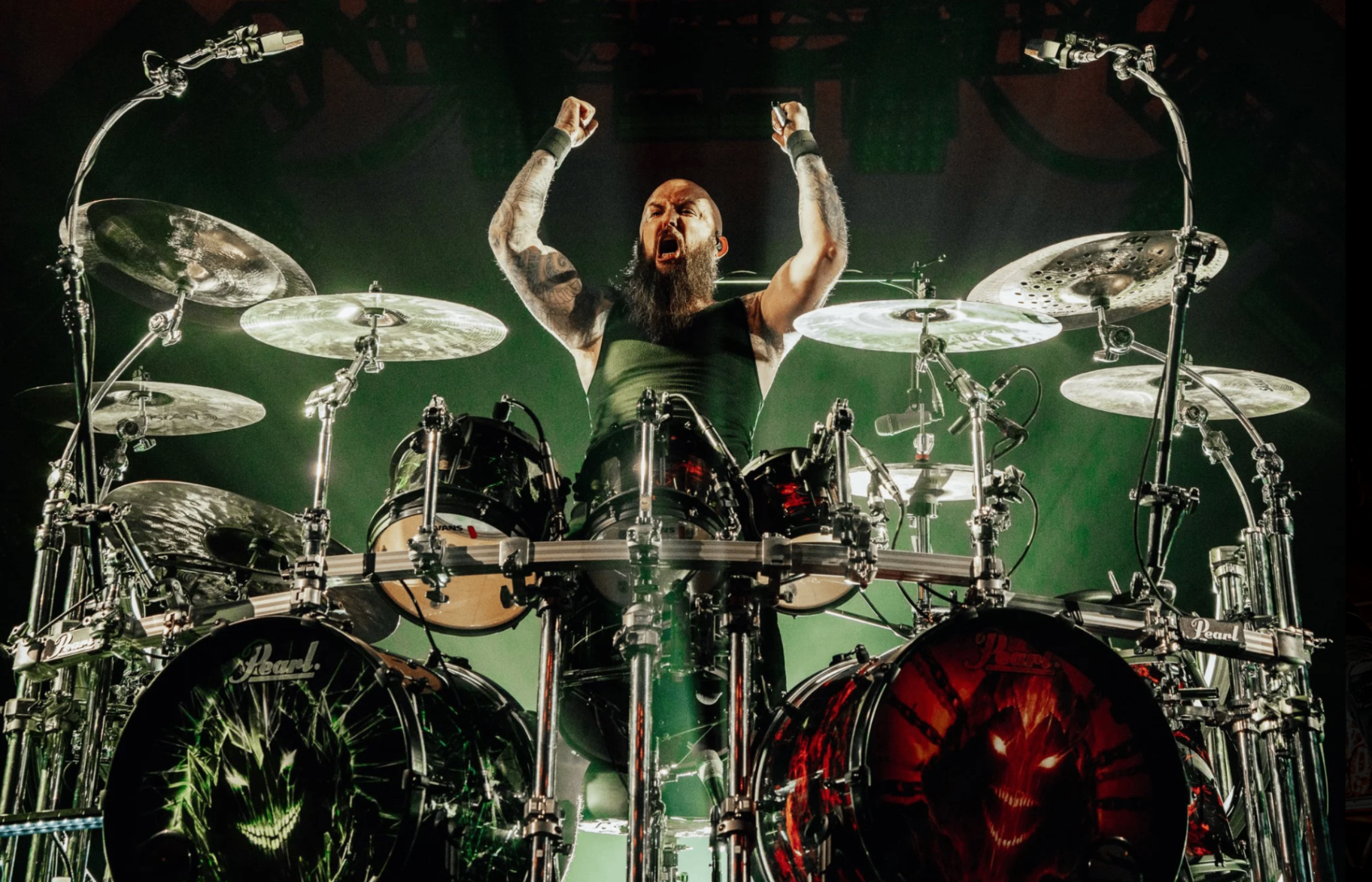 Drummer arms raised behind full kit